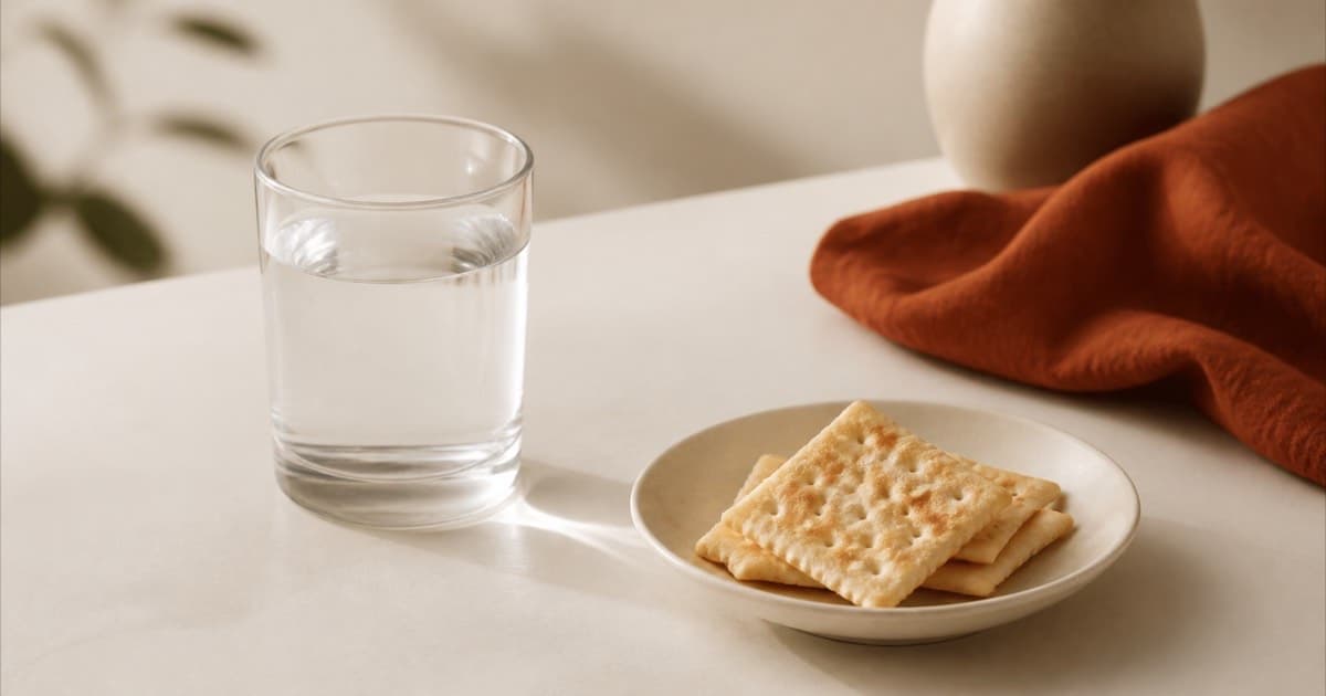 A glass of water and a small plate of plain crackers, calm still life