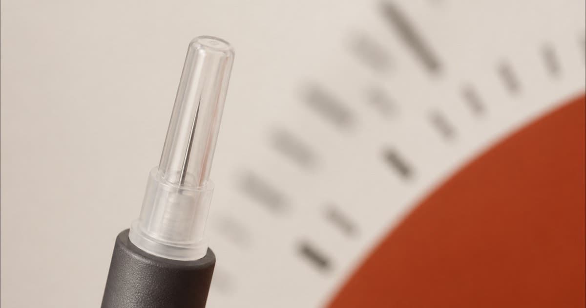 Macro photo of a fine pen needle tip next to a measuring scale